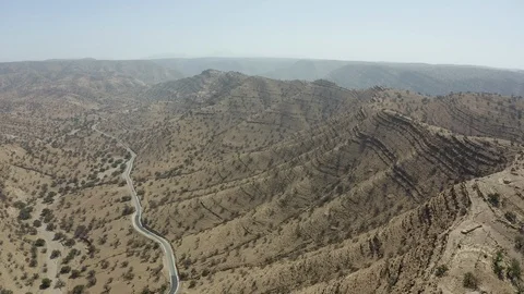 An aerial of a road cutting through a shallow desert valley towards mountains. Stock Footage 127013135