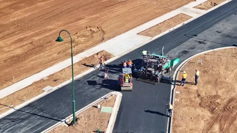 Aerial of road roller and worker tamping down hot asphalt behind a paving m.. Stock Footage 279355042