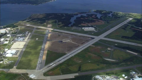 Aerial of roads passing through fields and warehouses, airplane flying over sea Stock Footage 109129563