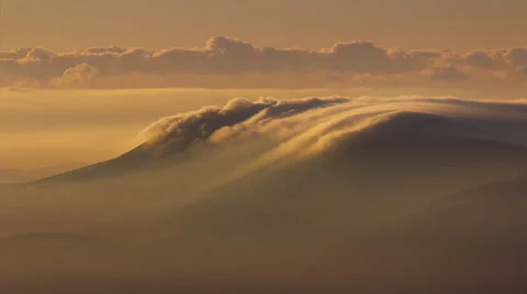 Aerial, rolling cloud vortex over mountain top at sunrise dawn Stock Footage 49945221