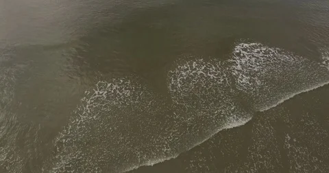 Aerial of rolling waves on a dark sandy beach Stock Footage 76676634