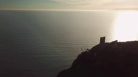 Aerial romantic view of a sunset over the sea with an ancient tower in backlight Stock-Footage 104490042