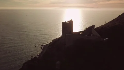 Aerial romantic view of a sunset over the sea with an ancient tower in backlight Stock Footage 104490162