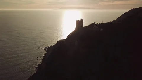 Aerial romantic view of a sunset over the sea with an ancient tower in backlight Stock Footage 104490211