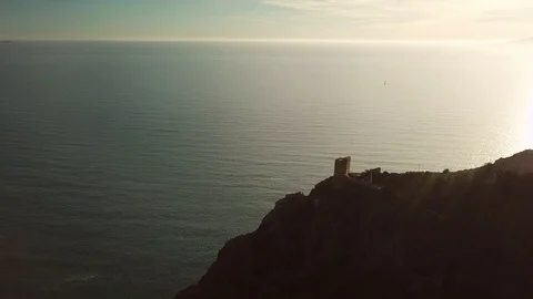 Aerial romantic view of a sunset over the sea with an ancient tower in backlight Stock-Footage 104490410