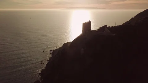 Aerial romantic view of a sunset over the sea with an ancient tower in backlight Stock Footage 104490449