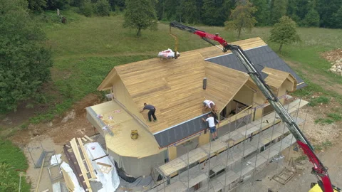 AERIAL: Roofers apply protective waterproof roofing sheets on a wooden house. Stock Footage 307840023