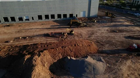 Aerial rotating shot, small backhoe digging construction site worker assisting Stock Footage 172333620