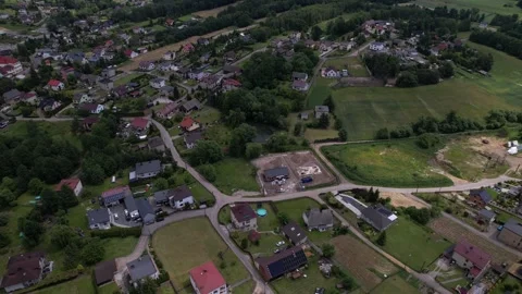 Aerial rotating shot of a small town surrounded by green fields and forests Vidéo 347802447