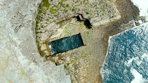 Aerial rotating top-down view of famous Poll na bPeist or the Wormhole, Ireland 스톡 동영상 247268390
