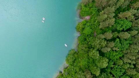 Aerial rotating top-down view of boats cruising along tropical lake shore. 스톡 동영상 279201581