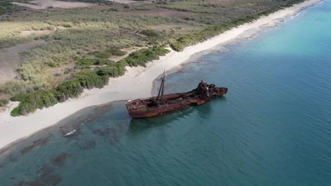 Aerial rotating view of rusty shipwreck beside remote island beach coast Stock Footage 343944778
