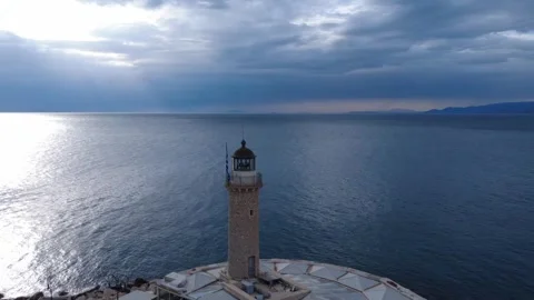 Aerial rotating wide shot of a lighthouse on a cliff during sunrise Stock Footage 338109259