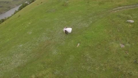 Aerial rotation panoramic view couple walking on green grass mist field. Cloudy Stock Footage 234453875