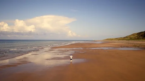 Aerial: Runner on remote beach. 4K Stock Footage 89723321