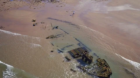 Aerial: Runner, wreck, beach. 4K Stock Footage 89689366