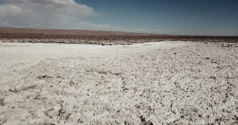 Aerial sails low over white salt towards a patch of grey evaporite Stock-Footage 87574580