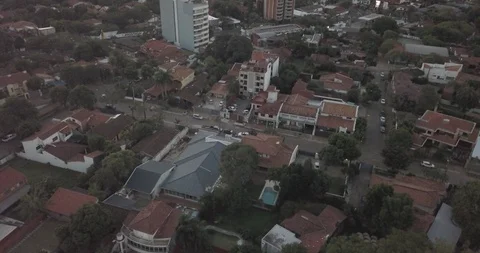 Aerial sails over brick rooftops of Asuncion and tilts up to reveal skyline Vídeos de archivo 92443816