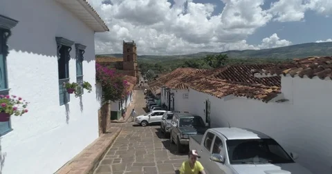 Aerial sails past open window and over rooftops towards church plaza Stock-Footage 82498038