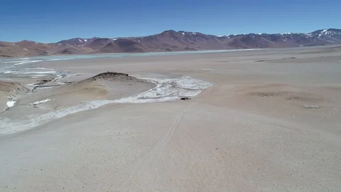 Aerial scene of 4x4 van driving off road beside white hot river with geysers 스톡 동영상 103453353