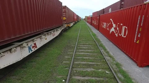 Aerial scene moving backwards through a train rail and flying over containers on Vídeo Stock 59995195
