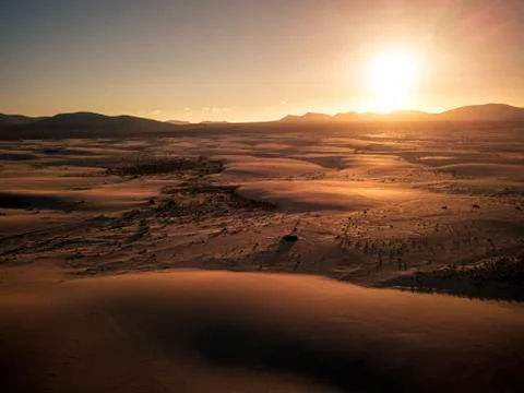 Aerial scenic landscape of sandy desert with dunes and sunset at the horizon  Stock Photos