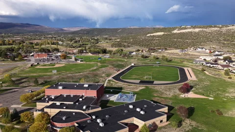 Aerial of school and homes in Cedaredge Colorado with stormy mountains Video stock 347317455