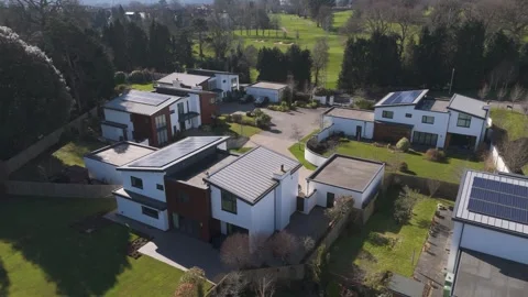 Aerial of secluded cluster of layered cube homes with wood cladding, fenced Stock Footage 310600222