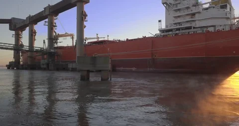 AERIAL: A ship loads grain in a river port at sunrise Vídeos de archivo 129789624