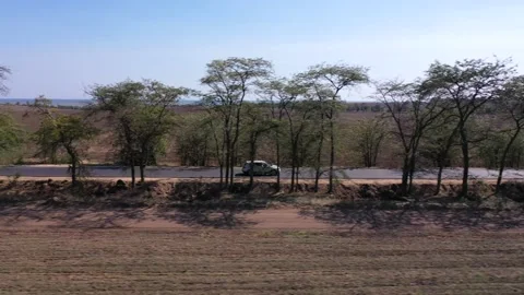 Aerial shoot from the side of moving white car road through fields Stock Footage 151653393