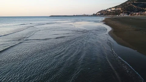 Aerial shooting of Waves lapping up against the shore in the sunset via drone Stock Footage 101600282