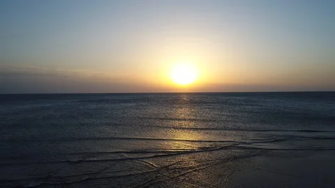 Aerial shooting of Waves lapping up against the shore in the sunset via drone Stock Footage 101601313