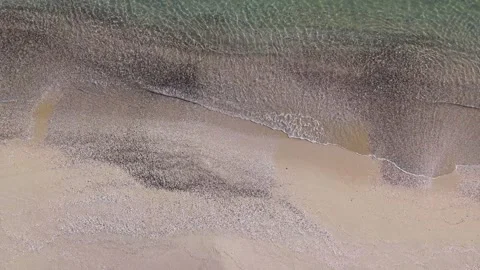 Aerial Shoreline Split View Waves Meeting Sand and Green Sea Stock Footage 325292048