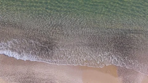 Aerial Shoreline Split View Waves Meeting Sand and Green Sea Stock Footage 325292054