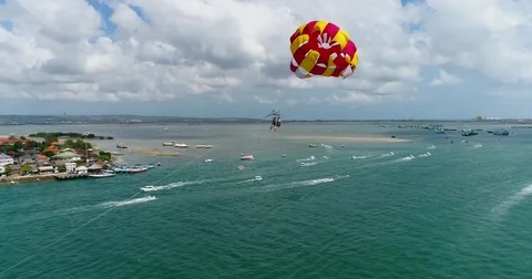 Aerial shot of 2 persons under a parasail getting towed by a boat Vídeo Stock 79821045