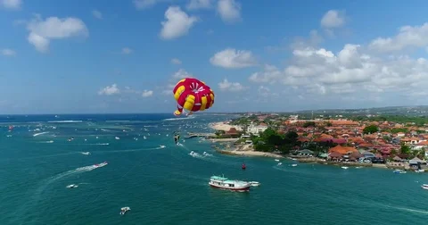 Aerial shot of 2 persons under a parasail getting towed by a boat Stock Footage 79821762