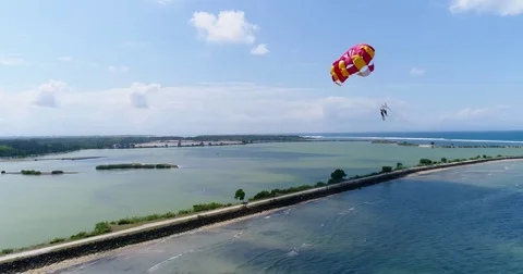 Aerial shot of 2 persons under a parasail getting towed by a boat 動画素材 79822154