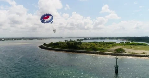Aerial shot of 2 persons under a parasail getting towed by a boat Stockbeeldmateriaal 79825193