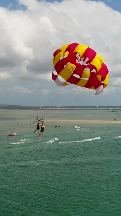 Aerial shot of 2 persons under a parasail getting towed by a boat Stock Footage 225520397