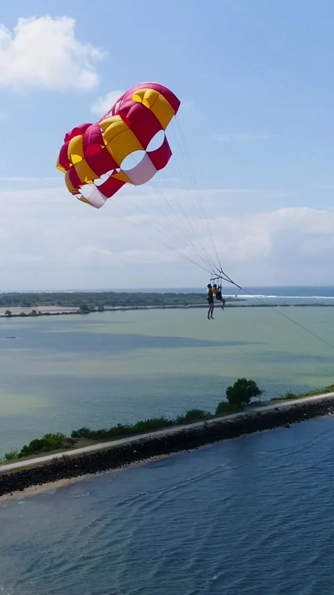 Aerial shot of 2 persons under a parasail getting towed by a boat 動画素材 225520408