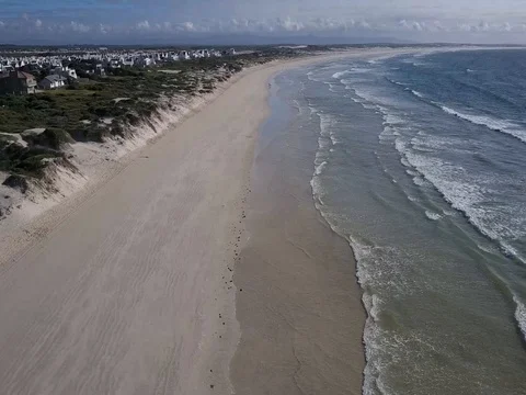 Aerial shot along an empty beach near a small coastal town Stock Footage 77614275