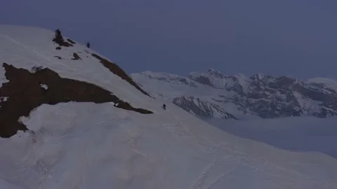 Aerial shot approaching a single man climbing to the top of a snowy mountain Stock Footage 196889771