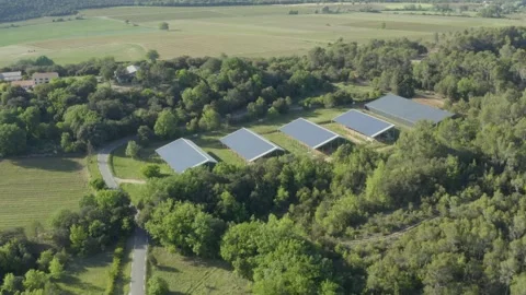 Aerial shot approaching a solar panel farm in a forest in the countryside Stock Footage 240979984