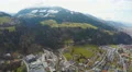 Aerial shot of big city, beautiful Alps around it, green downhills, snowy peaks 4k or 4k+ Resolution