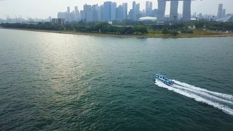Aerial shot of boat speeding through water with city background, Singapore Stock Footage 106599803