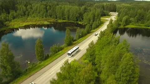 Aerial Shot of Bus Riding on Highway Surrounded by Large Forest Stock Footage