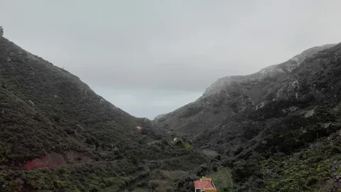 Aerial shot. Canyon between two hills. At the bottom of the canyon there are Stock Footage 104026982