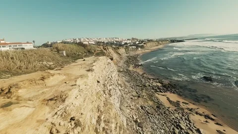 Aerial shot captures cliffside beach with gentle waves and sunlit rocks Stock Footage 339791771