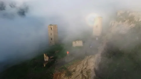 Aerial shot captures visitors exploring fog-enveloped ancient ruins. Misty Stock Footage 265051366