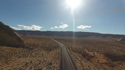 Aerial shot of car driving down desert highway Stockbeeldmateriaal 148604366